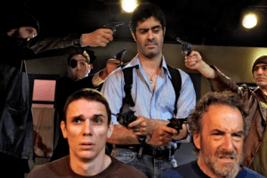 Padraic (Damien Seperi, center) searches for answers in the death of his beloved cat in the Masquers Playhouse production of “The Lieutenant pf Inishmore.” Padraic questions Joey (Alan Coyne, bottom left) and Donny (Avi Jacobson, bottom right) while under pressure from Brendan, Christy, and Joey (Jesse MacKinnon, David Stein, and Dan Kurtz). Photo Credit: Masquers Playhouse