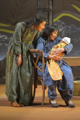 Mariam (Kate Rigg, seated) holds Laila’s (Nadine Malouf) newborn child. Photo credit: Kevin Berne